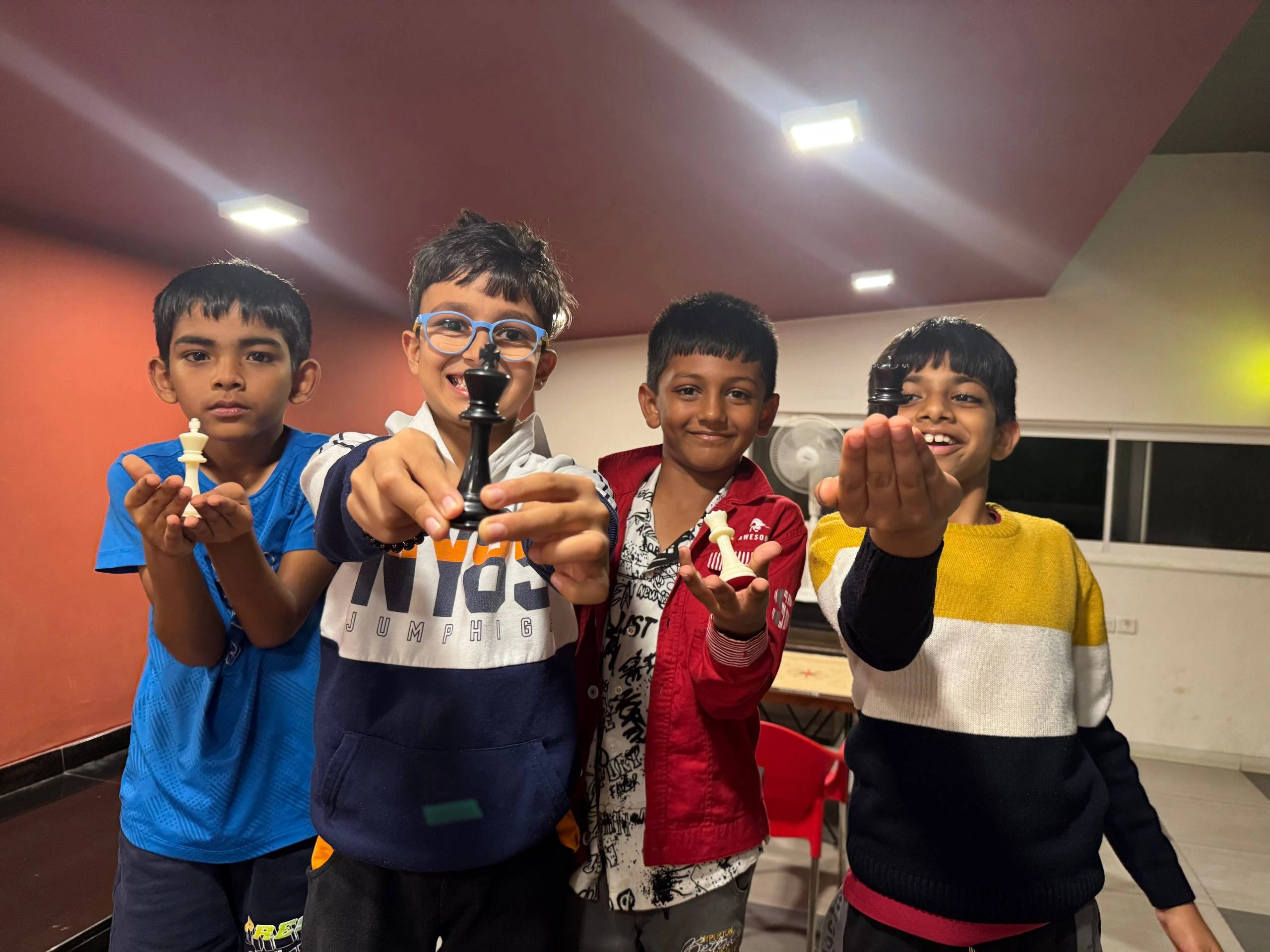 Happy children proudly showing their chess trophies at academy event